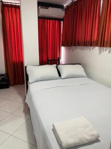 a white bed in a room with red curtains at BRYSS HOTEL in Santo Domingo de los Colorados +20 photos