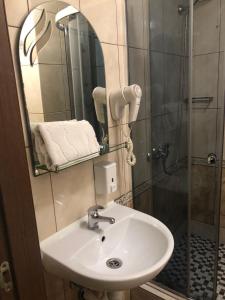y baño con lavabo y ducha con espejo. en Apart Hotel Avinos en Leópolis