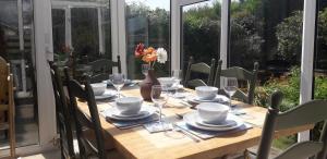 a wooden table with glasses and plates on it at Beautiful family getaway, close to the beach in Fairbourne