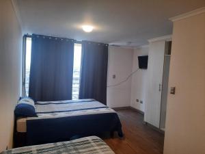 a bedroom with two beds and a window at Departamentos RO in Antofagasta