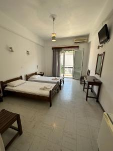 a bedroom with two beds and a television in it at Hotel Galini in Parga