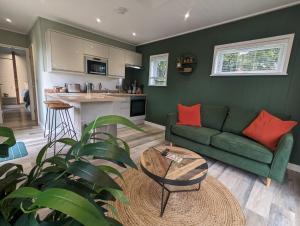 a living room with a green couch and a kitchen at Gosling Lodge in Durham