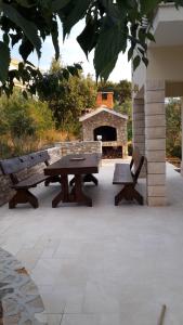 a picnic table and two benches in front of a fireplace at Apartments Kate in Nečujam