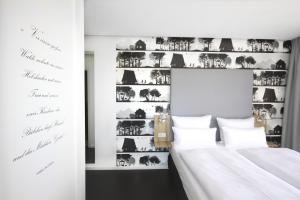 a bedroom with two beds and a wall with photographs at Grimm's Potsdamer Platz in Berlin