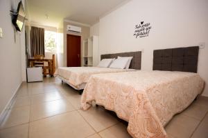 pokój hotelowy z 2 łóżkami i stołem w obiekcie Ribeiro Suit's Hotel w mieście Araxá