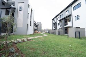 a building with a grassy yard next to a building at Stylish Apartment in Fourways in Sandton