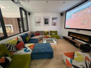 - un salon avec une grande télévision et un canapé dans l'établissement Magnifique maison contemporaine proche lac d’Aix, à Aix-les-Bains