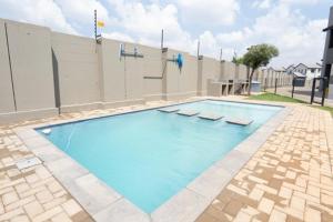 a swimming pool with blue water in front of a building at Stylish Apartment in Fourways in Sandton