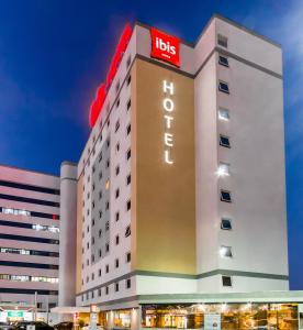 ein Hotelgebäude mit einem beleuchteten Hotelschild in der Unterkunft ibis Marilia in Marília