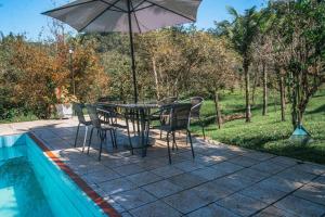 a table and chairs with an umbrella next to a pool at Recanto Dom José in Peruíbe