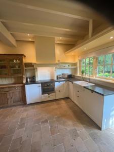 a large kitchen with white cabinets and a sink at Cottage Het Beukenootje in Aerdenhout