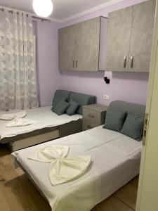 een kamer met 2 bedden en een keuken met kasten bij Apartment Shkoder in Shkodër