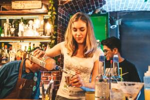 a woman pouring a drink at a bartender at Wild Rover La Paz in La Paz