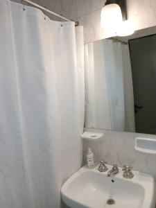 La salle de bains blanche est pourvue d'un lavabo et d'un miroir. dans l'établissement Comfy en Barrio Norte, à San Miguel de Tucumán