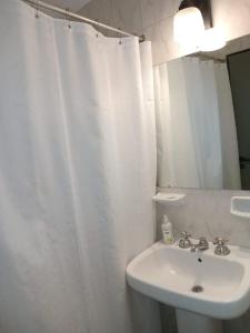 La salle de bains est pourvue d'un lavabo et d'un rideau de douche blanc. dans l'établissement Comfy en Barrio Norte, à San Miguel de Tucumán