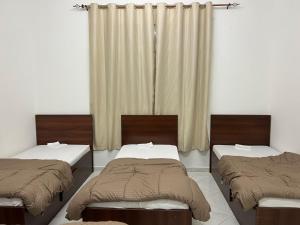 a room with two beds and a window with curtains at Short Stay Apartment in Dubai