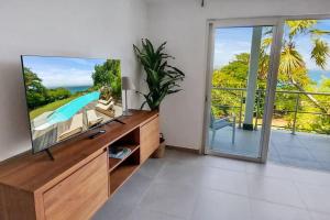 a living room with a tv and a sliding glass door at 7 bedrooms Villa, Nestled in the heights of Anse Marcel, one of the most discreet bays of the island. in Saint Martin