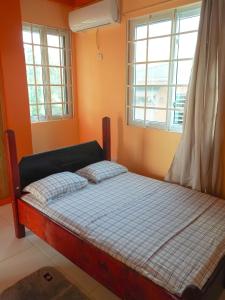 a bed in a room with two windows at RJ Residences in Roseau