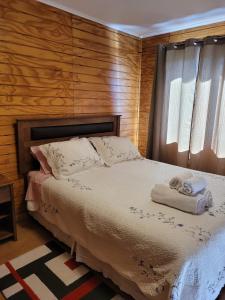 una camera da letto con un letto e due asciugamani di Cabañas ali a Puerto Aisén
