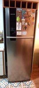 a stainless steel refrigerator with magnets and pictures on it at Apartamento Le Quartier - no centro, dois quartos, wi-fi, garagem, piscina, ar-condicionado, jacuzzi, sauna, etc in Juiz de Fora