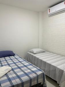 a bedroom with two beds and a wall with a heater at Flats do Lucca Tamandaré in Tamandaré