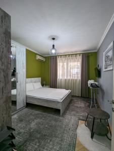 1 dormitorio con cama blanca y pared verde en Downtown Retreat "Spiranca" en Tirana