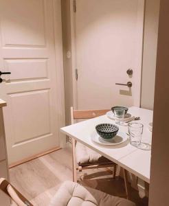 a white table with a bowl and plates on it at Cute little appartment in Kristiansand