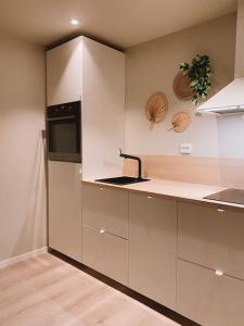 een keuken met witte kasten en een wastafel bij Cute little appartment in Kristiansand