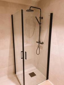 a shower with a glass door in a bathroom at Cute little appartment in Kristiansand