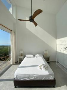 een witte slaapkamer met een bed en een plafondventilator bij Casa el Susurro - Barranquilla, Tubará in Tubará