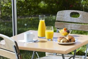 une table avec une assiette de nourriture et deux verres de jus d'orange dans l'établissement Campanile Béziers A9/A75, à Béziers