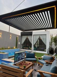 a patio with a couch and a table with a laptop on it at شاليهات كورال بارك in Al Kura