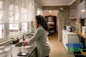 a woman standing at a sink in a kitchen at Atlântida Dream T1 in Angra do Heroísmo
