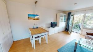 uma sala de estar com uma mesa e uma televisão em Deich-Residenz App. 6 em Grömitz