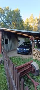 a car parked in front of a house with a fence at Domek pod lasem in Maniowy