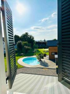 uma porta aberta para um quintal com uma piscina em Charme et détente avec piscine proche de Mulhouse em Flaxlanden