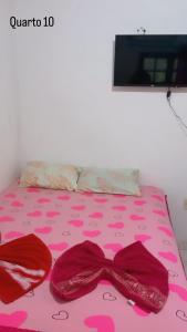 Una cama con una colcha rosa con una pajarita. en Beijaflor Pousada, en Corumbá