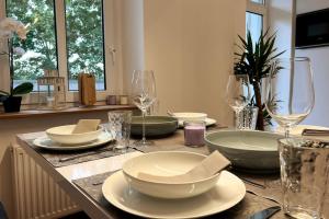 a table with plates and wine glasses on it at 4YOUnic: *2BR*55“TV*Balkon*Parkplatz in Leipzig