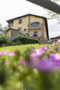 dom z fioletowymi kwiatami przed nim w obiekcie Country House La Mela Ruscalla w mieście Camino