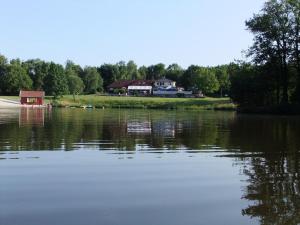 a view of a lake with a house in the background at Ferienwohnungen Liedtke in Behringen