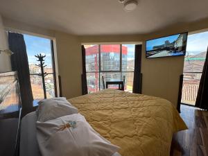 a bedroom with a bed and a tv and windows at Hotel Inka Palace Huayna Ccapac Cusco in Cusco