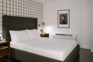 Un dormitorio con una gran cama blanca y un retrato de un hombre en Sonder at One Platt en Nueva York