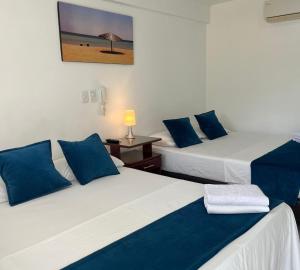 Habitación con 2 camas y sábanas azules y blancas. en Hotel Tucuraca by DOT Tradition, en Santa Marta