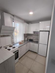 een keuken met witte kasten en witte apparaten bij Apartman LUXNS Novi Sad in Pasuljište