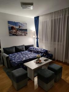 - un salon avec un lit et une table avec des tabourets dans l'établissement Apartman LUXNS Novi Sad, à Pasuljište