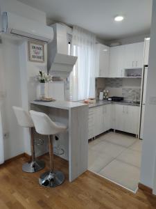 a kitchen with white cabinets and a counter with stools at Apartman LUXNS Novi Sad in Pasuljište