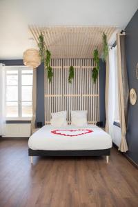 ein Schlafzimmer mit einem großen Bett mit weißer Bettwäsche und Blumen in der Unterkunft Grand studio avec spa, cosy et rénové au cœur de Soissons in Soissons