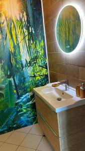a bathroom with a sink and a tropical mural at Grand studio avec spa, cosy et rénové au cœur de Soissons in Soissons