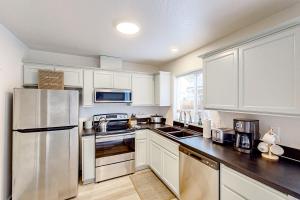 a kitchen with white cabinets and a stainless steel refrigerator at The Duck Den in Eugene