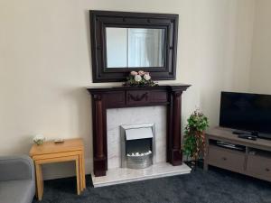 a living room with a fireplace with a mirror over it at Corner House 51 Go Go Street Ground Floor Largs KA308JW 2 Bedroom in Largs